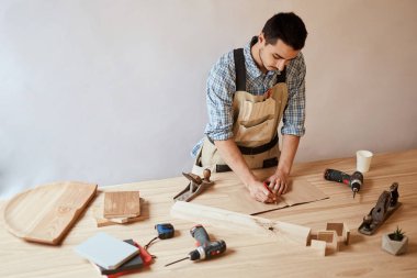 Carpenter man making draft plan using pencil on the table with tools clipart