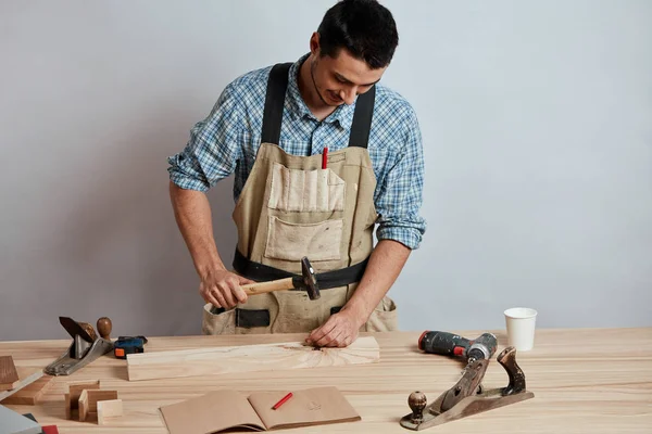 De timmerman hameren neer een spijker op houten plank, een meubels maken. — Stockfoto