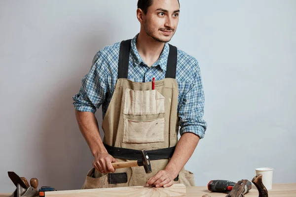 Il falegname che martella giù un'unghia a asse di legno, facendo mobili . — Foto Stock