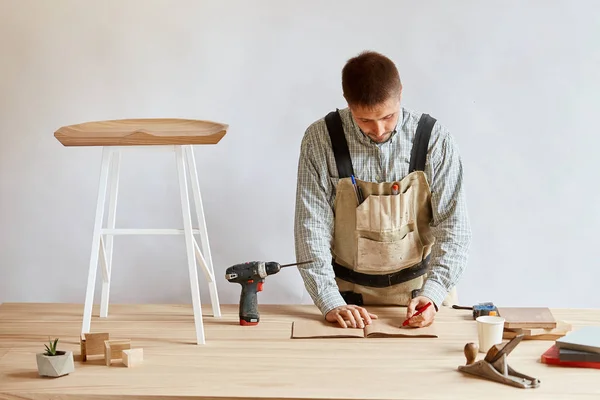 Hombre carpintero haciendo borrador plan usando lápiz sobre la mesa con herramientas — Foto de Stock