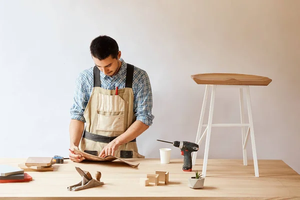 Hombre carpintero haciendo borrador plan usando lápiz sobre la mesa con herramientas — Foto de Stock