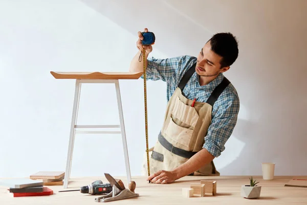 Mano de un carpintero que mide una tabla de madera — Foto de Stock