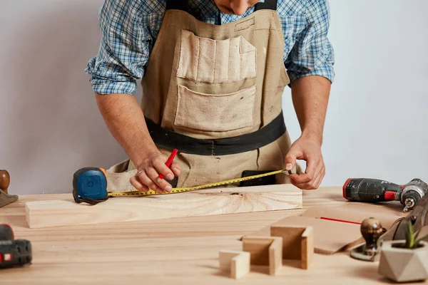 Junger Mann misst Wohnmöbel mit Maßband. Reparaturkonzept. — Stockfoto