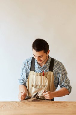 Marangoz odunla çalışıyor. Stüdyoda beyaz duvara karşı uçak kullanıyor..