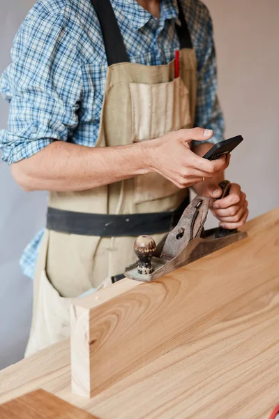 Carpintero trabajando con madera usando plano contra pared blanca en estudio. — Foto de Stock