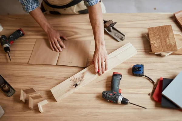 Closeup view of a carpenter using a red pencil to draw a line on a blueprint — Stock Photo, Image