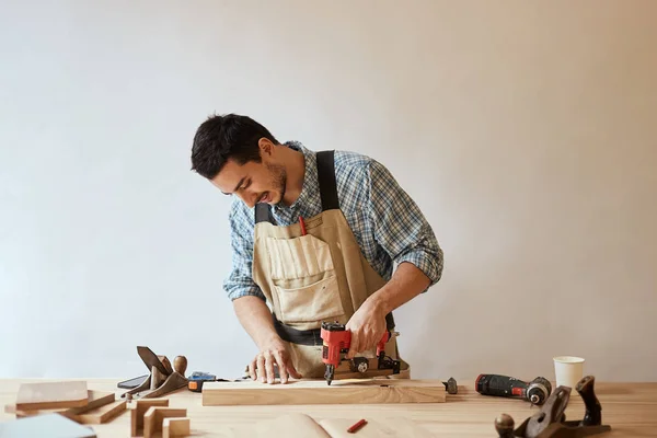 Carpenter drills a hole with an electrical drill — Stock Photo, Image