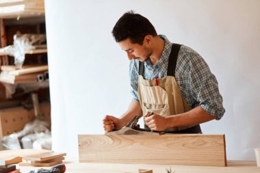 Marangoz odunla çalışıyor. Stüdyoda beyaz duvara karşı uçak kullanıyor..