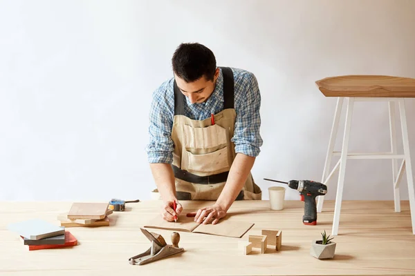 Timmerman man die ontwerpplan met potlood op tafel met hulpmiddelen — Stockfoto