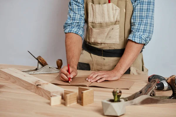 Closeup view of a carpenter using a red pencil to draw a line on a blueprint — Stock Photo, Image