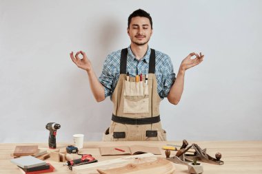 Tatmin olmuş marangoz, işten önce meditasyon yapıyordu. Parmakları katlanmış mudra hareketiyle..