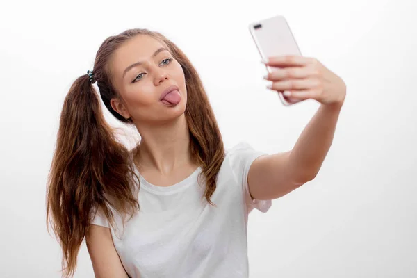 Divertida, chica impresionante mostrando su lengua mientras toma selfie — Foto de Stock