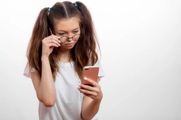 Joven chica linda seria sosteniendo el teléfono celular y buscando el wi-fi — Foto de Stock