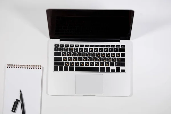Beyaz arka plan üzerinde dizüstü bilgisayar, boş defter ve kalem üstten görünüm. — Stok fotoğraf