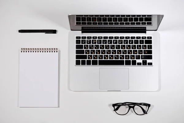 Bovenaanzicht van een witte office-tabel met een pen, opmerking, laptop- en glazen — Stockfoto