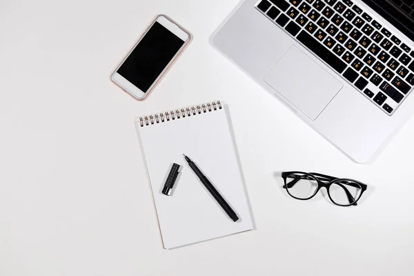 Mesa de escritório com notebook, MacBook, caneta, óculos e telefone inteligente — Fotografia de Stock