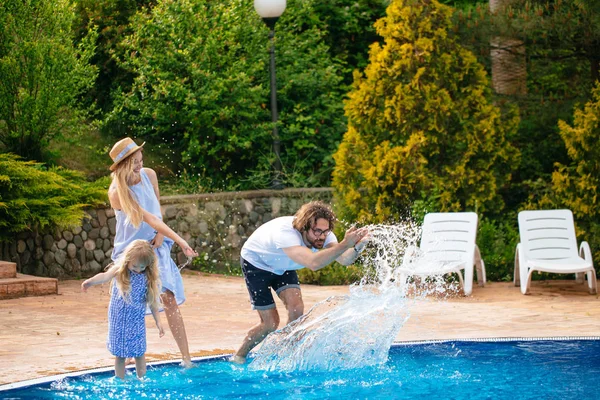 Família se divertindo sua piscina. família espirrando água com pernas ou mãos na piscina — Fotografia de Stock