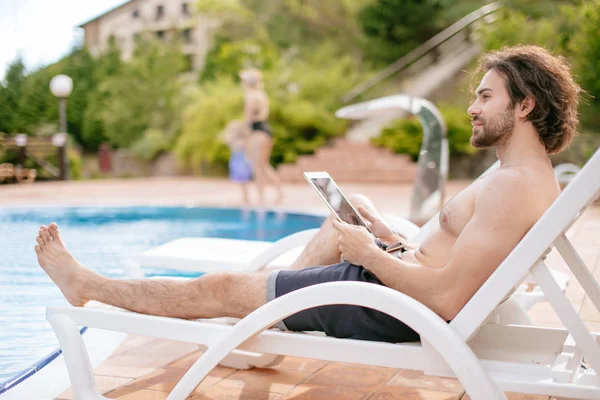 Empresário descansando no solário perto da piscina enquanto trabalhava remotamente no computador portátil conectado à internet sem fio — Fotografia de Stock