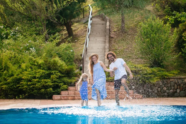 Família se divertindo sua piscina. família espirrando água com pernas ou mãos na piscina — Fotografia de Stock