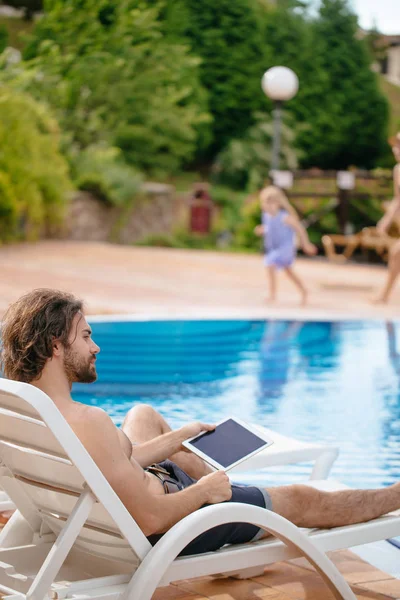 Empresário descansando no solário perto da piscina enquanto trabalhava remotamente no computador portátil conectado à internet sem fio — Fotografia de Stock