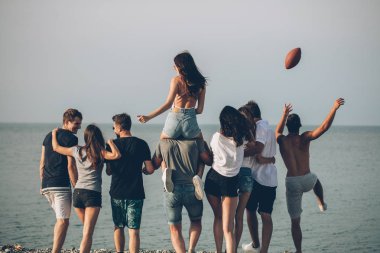 Mutlu erkekler ve kadınlar plajda yürüyüş yapar arkadaşlarıyla plaj tatilinin tadını çıkarırlar.