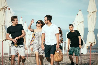 Tatil, tatil. Bir grup arkadaş sahilde eğleniyor, yürüyor, bira içiyor, gülümsüyor ve sarılıyorlar.