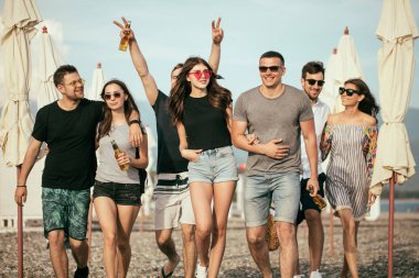 Tatil, tatil. Bir grup arkadaş sahilde eğleniyor, yürüyor, bira içiyor, gülümsüyor ve sarılıyorlar.