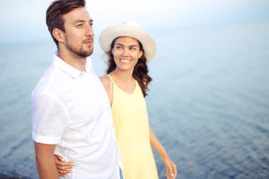 Kumsalda el ele tutuşan ve birlikte yürüyüp eğlenen çift.