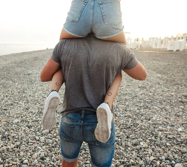 Mujer sentada en el cuello de su novio. Familia divertirse en la playa —  Fotos de Stock