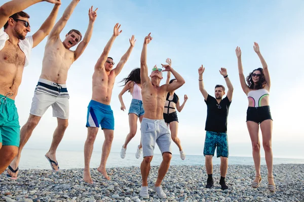 Amigos bailan en la playa bajo la luz del sol puesta del sol, divertirse, feliz, disfrutar — Foto de Stock