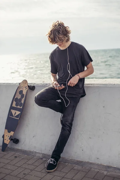 Ahşap longboard beton duvara tutan t-shirt giyen erkek görünümlü yan — Stok fotoğraf