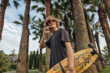 el ile Longboard yürümek ve konuşmak telefon kaykaycı