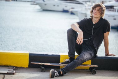 ile longboard Street pier yat ile üzerine oturan adam