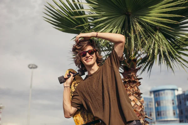 Man standing with skateboard on his shoulder and looking aside — Stock Photo, Image