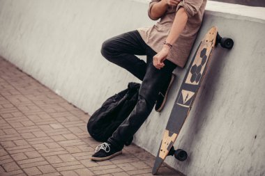ahşap longboard beton duvara tutan t-shirt giyen erkek görünümlü yan