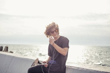 ahşap longboard beton duvara tutan t-shirt giyen erkek görünümlü yan