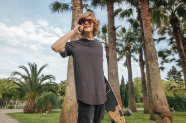 el ile Longboard yürümek ve konuşmak telefon kaykaycı