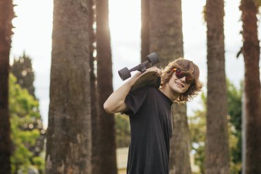onun omuz üzerinde kaykay ile ayakta ve bir kenara arayan adam