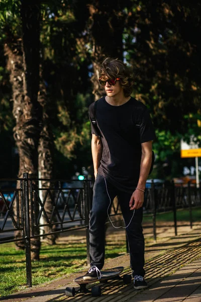 ロングボードに乗って遊歩道、暖かい夏の時間の少年 — ストック写真
