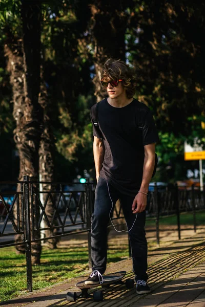 Boy riding longboard on boardwalk, warm summer time — Stock Photo, Image