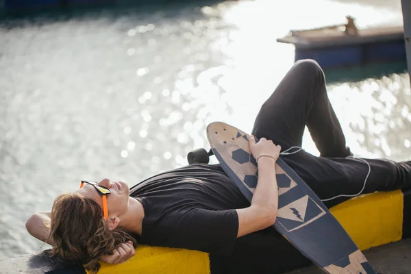 Young guy lying on skateboard spending time at skatepark — Stock Photo, Image