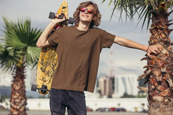 Man permanent met skateboard op zijn schouder en opzij op zoek — Stockfoto