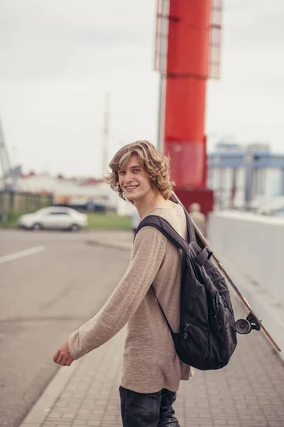 Man står med skateboard på hans axel och tittar åt sidan — Stockfoto