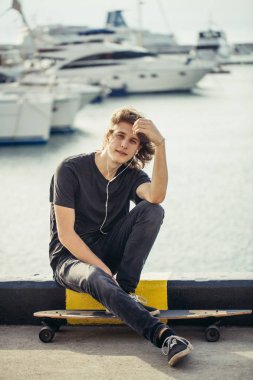 ile longboard Street pier yat ile üzerine oturan adam