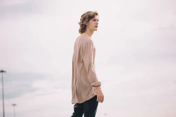 Joven hombre guapo sonriendo al aire libre en el fondo del cielo — Foto de Stock