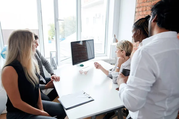 Ontwerpers verzamelen rond de tafel In vergadering op zoek op scherm — Stockfoto