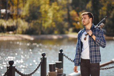 çubuk ve gölde balık tutma güneş gözlüğü ile genç balıkçı