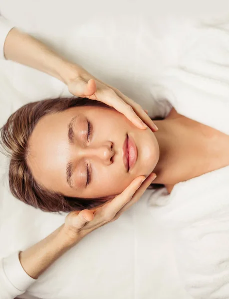 Awesome young woman with closed eyes enjoying face massage in the spa center — Stock Photo, Image
