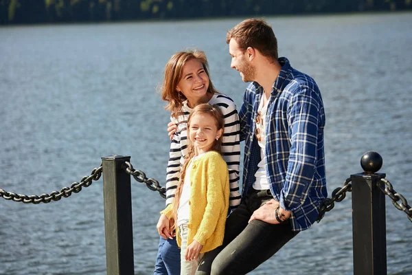 Happy Family looking at camera while posing on pier at quiet lake