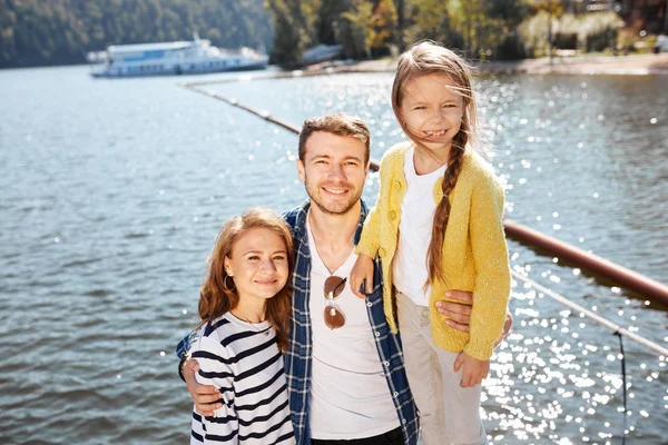 Happy Family looking at camera while posing on pier at quiet lake